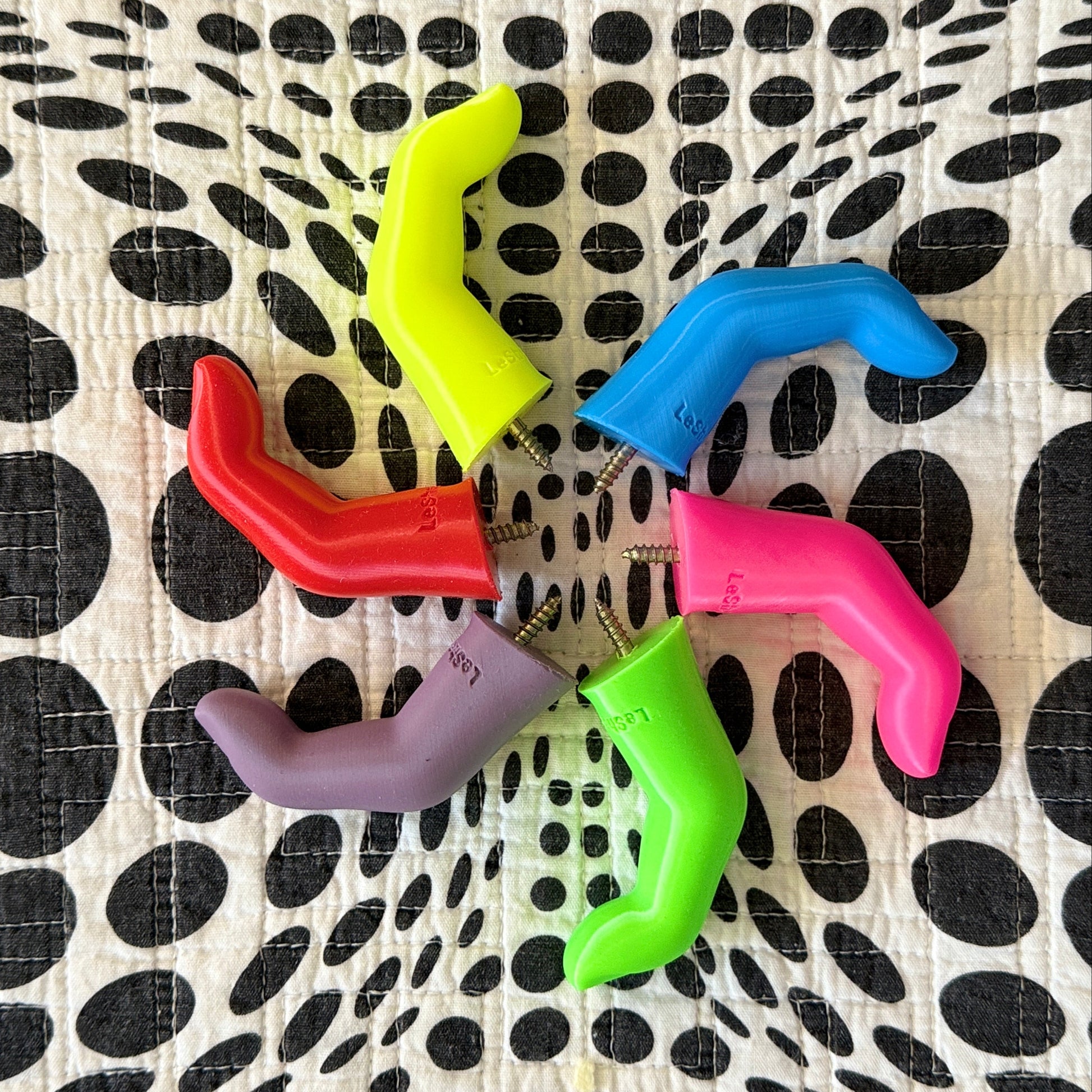 Colorful plastic finger shaped wall hooks on a black and white polka dot background